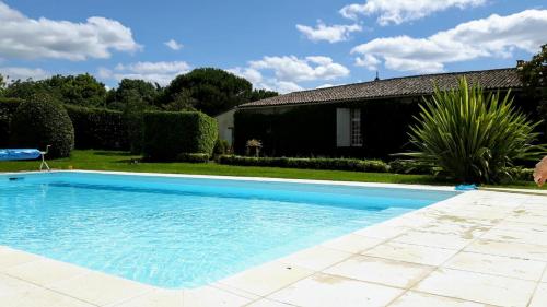 a large blue swimming pool in front of a house at La Jouissiere in Soulignac