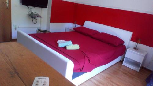 - un lit rouge et blanc avec 2 serviettes dans l'établissement Rooms & Studio, à Supetar
