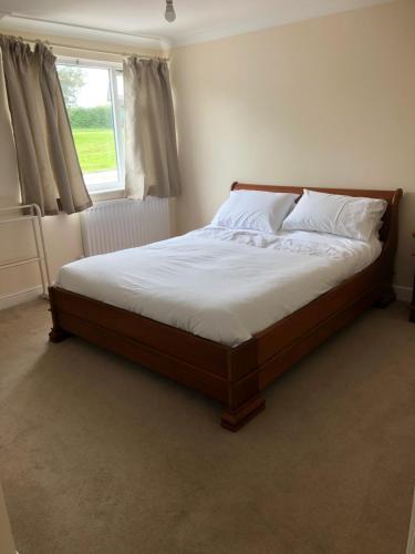 a bedroom with a bed with white sheets and a window at Henry,s Place in Great Torrington