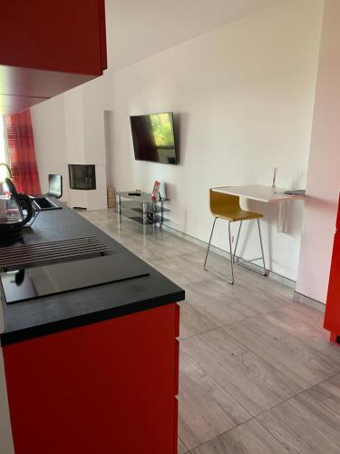 a kitchen with a red counter top and a living room at Yacht Club Apartamenty in Radzyń