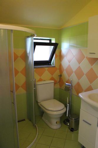 uma casa de banho com um WC, uma janela e um lavatório. em Aura em Jadranovo