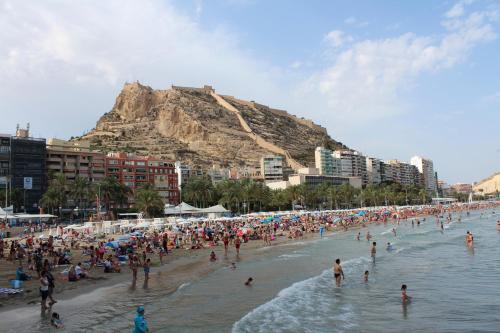 a crowd of people on a beach with a mountain at Mendez Nuñez Alicante in Alicante
