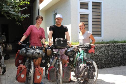 três pessoas de pé com as suas bicicletas em frente a uma casa em Park Hostel Osh em Osh