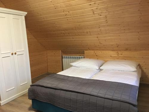 um quarto com uma cama num quarto de madeira em Wygodny murowany domek- NOWY em Dąbki