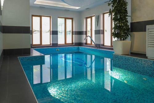 una piscina con suelo de baldosa azul y ventanas en Hotel & Spa PALIĆ RESORT en Palić
