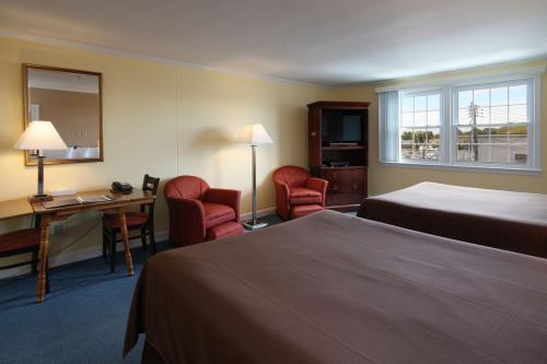 a hotel room with two beds and a desk and chairs at Cape Cod Harbor House Inn in Hyannis