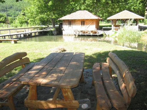 a wooden picnic table and two chairs in front of a pond at Vodenica Lug in Strmosten