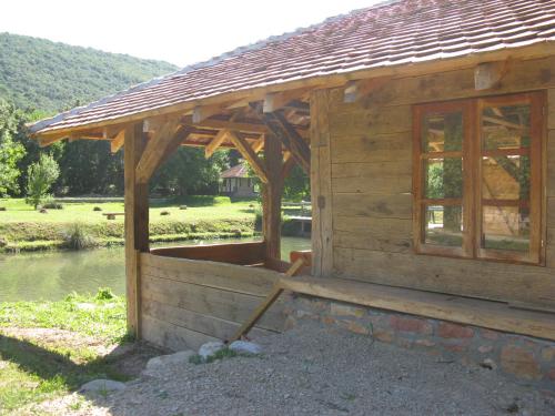 a small wooden cabin with a roof on a lake at Vodenica Lug in Strmosten