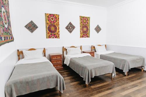 Habitación con 3 camas y pinturas en la pared. en Trip.LE Hostel Samarkand, en Samarkand