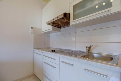 a kitchen with white cabinets and a sink at Apartment Jasna Near Čikat Bay and Center with Private Parking in Mali Lošinj