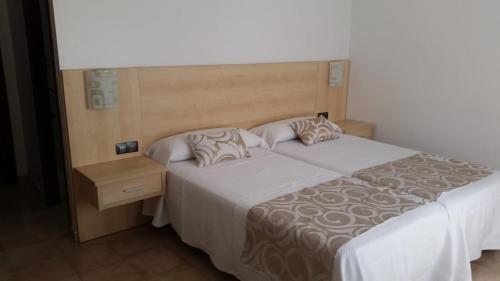 two beds in a hotel room with white sheets and pillows at Hotel Rias Baixas in Sanxenxo