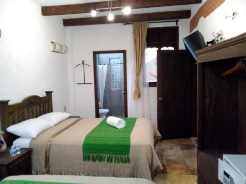a bedroom with a bed with a green blanket at Hotel Na´Lum in San Cristóbal de Las Casas