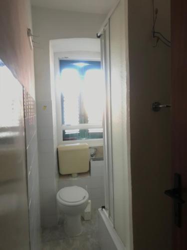 a small bathroom with a toilet and a window at Apartman Gracin in Primošten