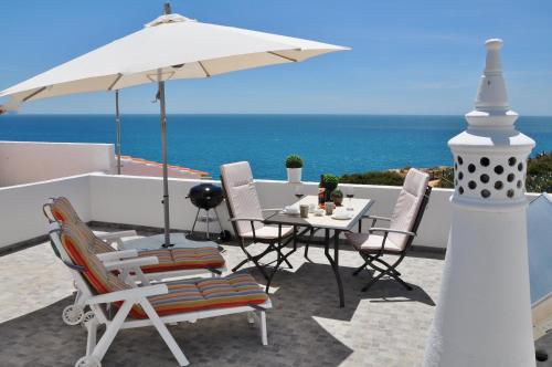 a table and chairs with an umbrella and the ocean at Casa Miguel in Carvoeiro