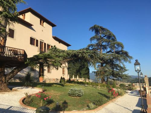 una casa con un grande albero di fronte di Villa D'Arte Agri Resort a Pontassieve