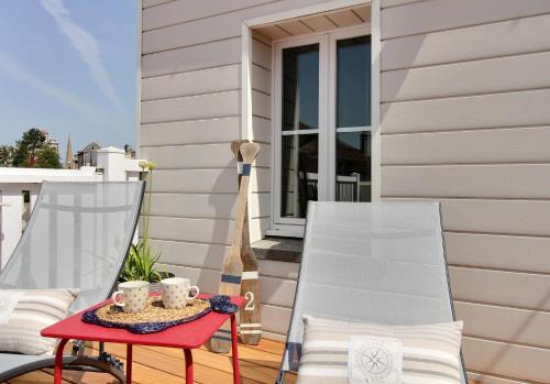 a patio with two chairs and a table with cups at La Cabine De La Baie in Saint-Pair-sur-Mer