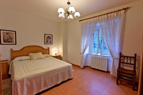 een slaapkamer met een bed, een raam en een stoel bij Casa Cazoleiro in Meira
