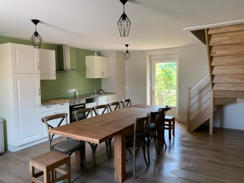 une cuisine et une salle à manger avec une table et des chaises en bois dans l'établissement La maison des Légendes, à Paimpont