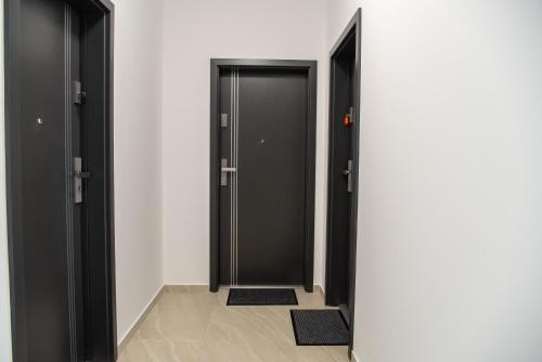 a hallway with two black doors and two mats at Apartments Steel Residence -Tesla Test Drive and 120 kW Supercharger in Timişoara