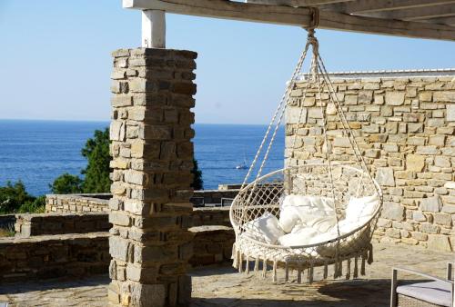a swinging chair on a patio with the ocean in the background at Sunset Villa II in Nea Cryssi Akti