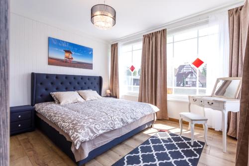a bedroom with a bed and a desk and windows at Villa Rosalie in Pärnu