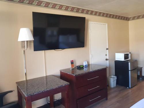 a hotel room with a flat screen tv on the wall at Travelodge by Wyndham Costa Mesa Newport Beach Hacienda in Costa Mesa