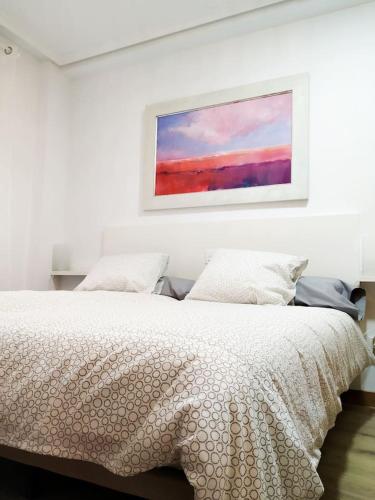 a white bedroom with a bed with a painting on the wall at Living Burgos in Burgos