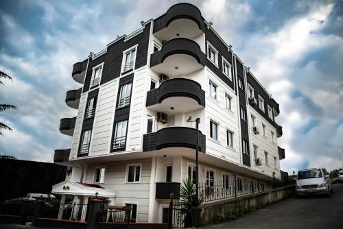 duży biały budynek z zaparkowanym przed nim samochodem w obiekcie Nova Suite Residence w mieście Trabzon