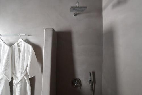 a white robe hanging on a rack in a bathroom at Thiro Santorini in Fira