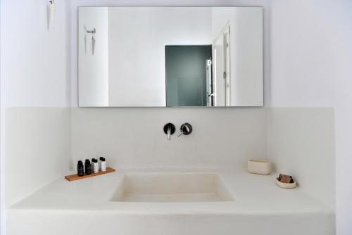 a white bathroom sink with a mirror above it at Thiro Santorini in Fira