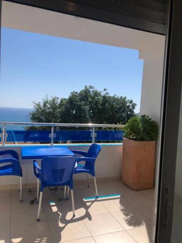 a balcony with a blue table and chairs and the ocean at Apartmani Dini in Ulcinj