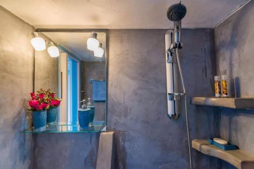 a bathroom with a shower with a mirror and flowers at BLUE PARADISE SUITES in Pachaina