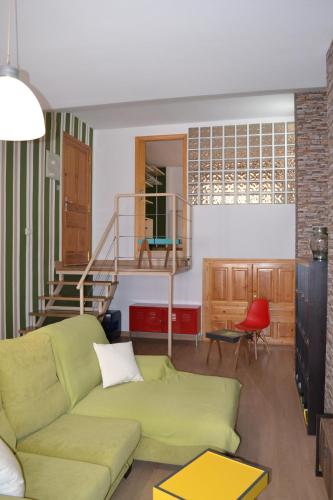 sala de estar con sofá verde y escalera en Apartamento Puerta del Pirineo, en Sabiñánigo
