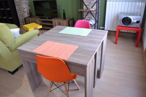 a wooden table with an orange chair in a living room at Apartamento Puerta del Pirineo in Sabiñánigo