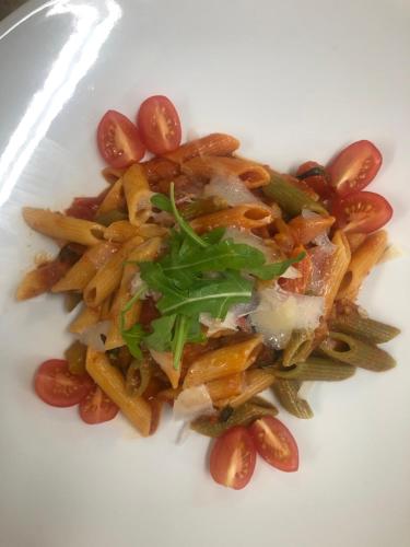 a white plate of food with pasta and tomatoes at Hotel & Gastropark Loemühle in Marl