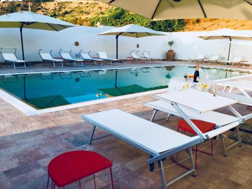 einen Pool mit Tischen, Stühlen und Sonnenschirmen in der Unterkunft Villaggio Imbesi in Villa San Giovanni