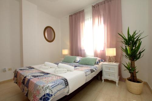 a bedroom with a bed with a plant and a window at Apartamento Mar De L'est 450 m de la playa con piscina in Gandía