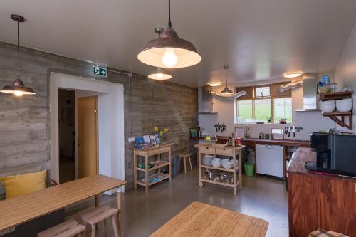 uma grande cozinha com mesas de madeira e um balcão em Skyrhusid HI Hostel em Hali
