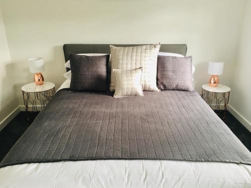 a large bed with two lamps on two tables at 1 Shiphouse Apartment in Lamlash