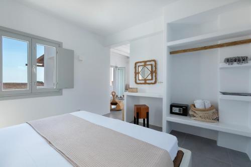 a white bedroom with a bed and a window at Bianco Diverso Suites in Imerovigli