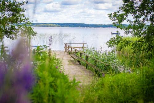 a wooden bridge over a lake with a boat on it at Karlskoga Folkhögskola Vandrarhem Udden in Karlskoga