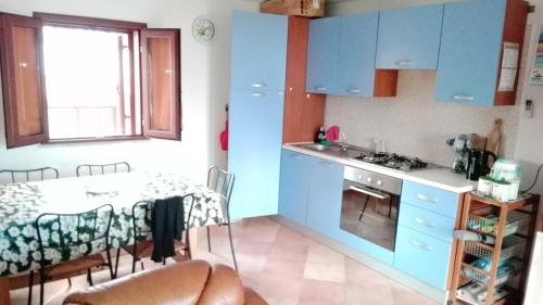 努奧羅的住宿－Appartamento Posada，厨房配有蓝色橱柜、桌子和窗户。