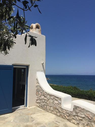 a white building with a blue door and the ocean at Seafront Villa Polyxene in Keratea