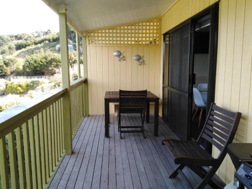 a porch with a wooden table and chairs on it at Whatuwhiwhi TOP 10 Holiday Park in Tokerau Beach