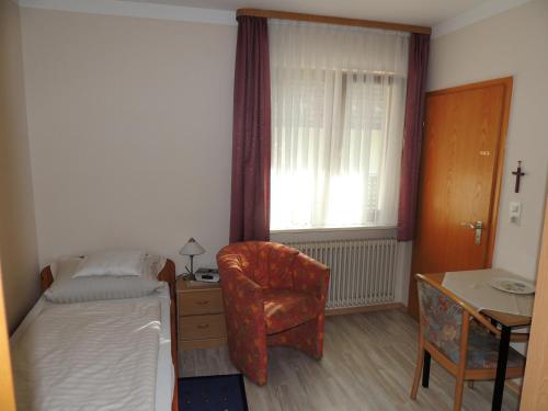 a bedroom with a bed and a chair and a desk at Gästehaus und Ferienwohnung Bächle in Bad Peterstal