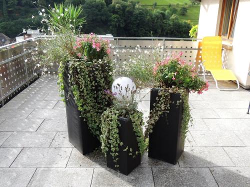 a patio with three black containers filled with plants at Gästehaus und Ferienwohnung Bächle in Bad Peterstal