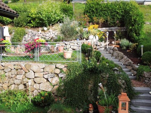 a garden with a stone wall and some plants and flowers at Gästehaus und Ferienwohnung Bächle in Bad Peterstal