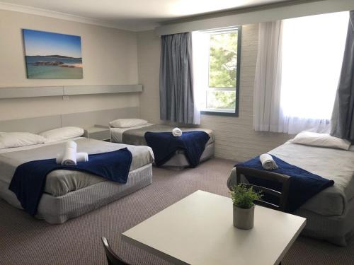 a hotel room with three beds and a table at Seabreeze Beach Hotel in South West Rocks