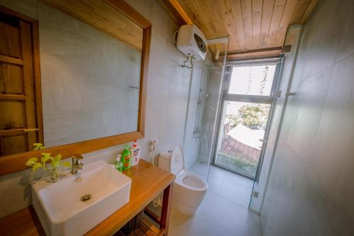 a bathroom with a sink and a toilet and a mirror at The Purple Hue Homestay in Hue