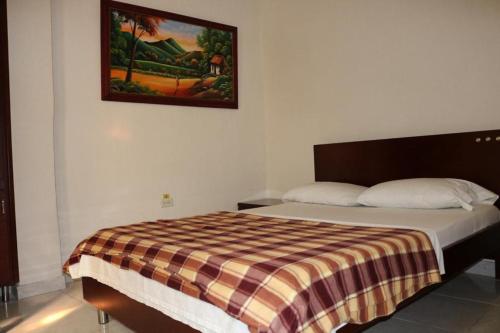 a bed in a bedroom with a picture on the wall at Aparta Hotel Puerto Nuevo in Barrancabermeja